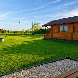 a log cabin with a yard with a grass field at Witówka Bieliny in Bieliny