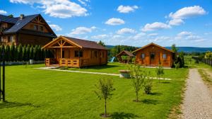 a group of wooden cabins on a green lawn at Witówka Bieliny in Bieliny