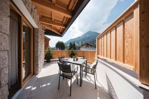 a patio with a table and chairs on a balcony at AlpeLuce Mountain Chalet in Arabba