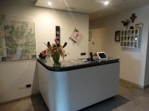 a reception desk with a vase of flowers on a counter at Garnì Ischia in Nago-Torbole