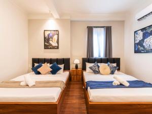 a bedroom with two beds with blue pillows at Gon De Home Ham Nghi in Ho Chi Minh City
