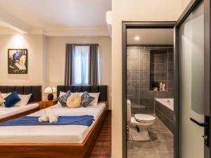 a bedroom with two beds and a bathroom at Gon De Home Ham Nghi in Ho Chi Minh City
