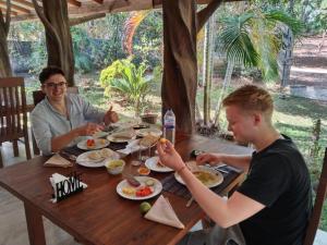 two men sitting at a wooden table eating food at Ela Addara Green Villa in Sigiriya +47 photos