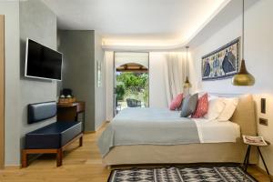 a bedroom with a bed and a chair and a television at Hotel delle Rose a Luxury Boutique Hotel in Porto Cervo