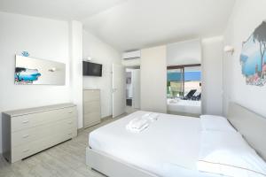 a white bedroom with a bed and a tv at NRH Cannigione Sunrise Rooftop in Cannigione