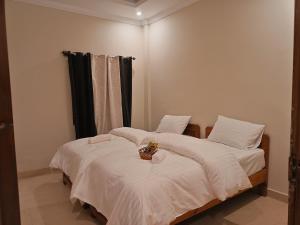 two beds with white sheets and a basket on top at Sunset View Luxury Apartments in Nathia Gali