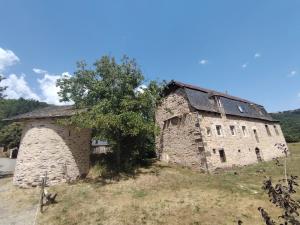 an old stone building in a field with a tree at Lo Castel de Lasmaries in Saint-Parthem
