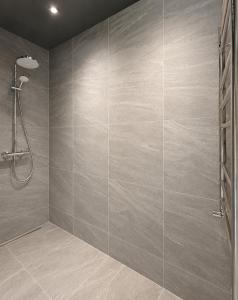 a bathroom with a shower and a tile wall at Green Guest House in Sigulda