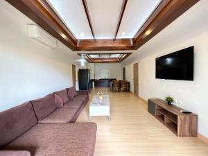 a living room with a couch and a flat screen tv at Panya Samui in Choeng Mon Beach