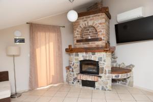 a stone fireplace in a living room with a tv at Apartments Ribarica in Karlobag