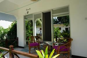 a porch with chairs and a table and windows at Cocolala Beach House in Nungwi