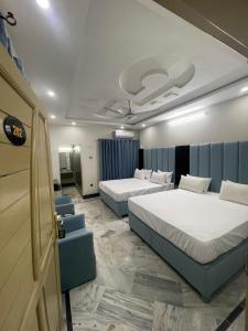 a hotel room with two beds and a room with two chairs at Aban Guest House in Peshawar