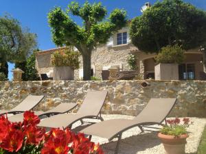 une rangée de chaises blanches devant un mur en pierre dans l'établissement Bastide de Fontvieille, à Saint-Cyr-sur-Mer