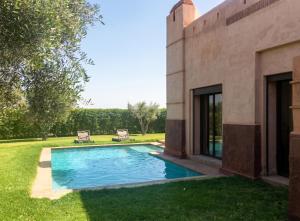 a swimming pool in a yard next to a house at Elegant Villa in Marrakech with a Private Pool. in Douar bel Rhanodour