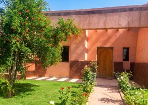 a house with an orange tree in the yard at Elegant Villa in Marrakech with a Private Pool. in Douar bel Rhanodour