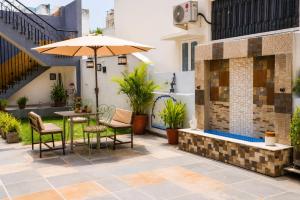 a patio with a table and chairs and an umbrella at Hotel Atithya in Udaipur