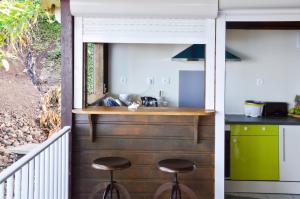 a kitchen in a house with stools in front of a counter at Bungalow confortable avec vue mer à Bouillante in Bouillante