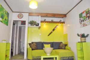 a living room with a yellow couch and a baseball bat on the wall at Bungalow confortable avec vue mer à Bouillante in Bouillante