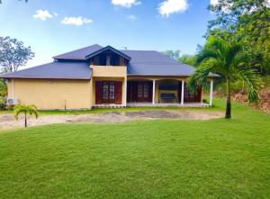 a house with a palm tree in front of a yard at Maison conviviale à Deshaies avec piscine partagée 120 m² in Deshaies