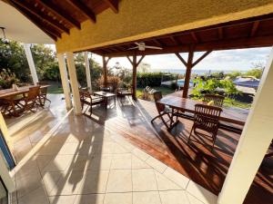 an outdoor patio with wooden tables and chairs at Maison conviviale à Deshaies avec piscine partagée 120 m² in Deshaies
