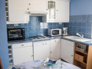 a kitchen with white cabinets and a sink and a microwave at Appartement avec piscine partagée à Roquefort-la-Bédoule - 50m² in Roquefort-la-Bédoule +29 photos