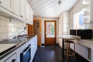 a kitchen with white cabinets and a sink and a table at Malgré tout 2 in Salvan