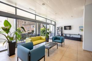 a living room with a yellow couch and blue chairs at Hotel Muralto Locarno in Locarno