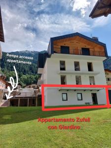 a white building with a brown roof on top of it at Appartamento ZUFALL in Cogolo