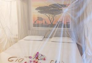 a bed with white sheets and flowers on it at Spacious accessible house in Watamu, shared pool in Watamu