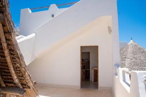 a white house with a staircase and a pyramid at Spacious accessible house in Watamu, shared pool in Watamu +19 photos