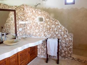 a bathroom with a sink and a stone wall at Spacious accessible house in Watamu, shared pool in Watamu