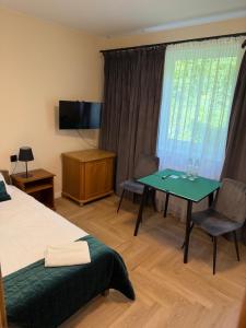 a room with a bed and a table and a television at Hotel Baltazar Pułtusk in Pułtusk