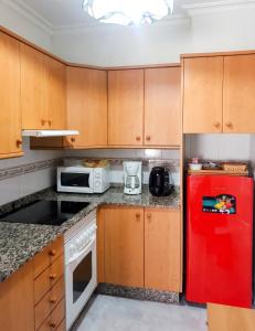 a kitchen with a red refrigerator and a microwave at Charming Apartment in El Grove, Sea View in O Grove