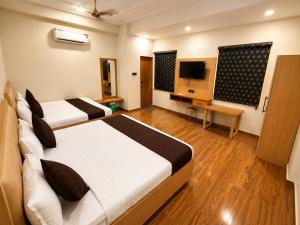 a hotel room with two beds and a television at Hotel Param INN in Gwalior