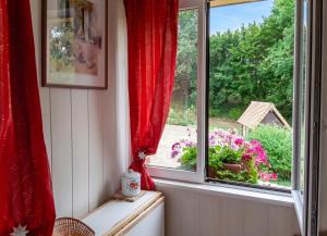 a room with a window with red curtains and flowers at Appartement cosy aux Authieux Papion 15 m² avec jardin privatif in Les Authieux-Papion +7 photos