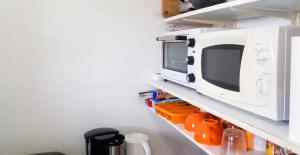 a kitchen shelf with a microwave on top of it at Studio charmant à Sainte-Anne avec piscine privée, 25 m² in Sainte-Anne +10 photos