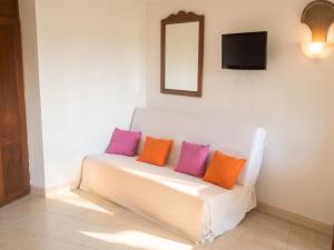 a white couch with purple and orange pillows on it at Studio charmant à Sainte-Anne avec piscine privée, 25 m² in Sainte-Anne