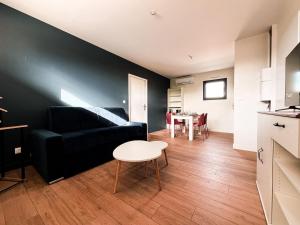 a living room with a black couch and a table at Claïla Appart-Hôtel Abzac in Abzac