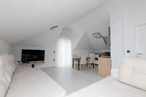 a white living room with a white couch and a television at Apartments ANA Karlobag in Karlobag