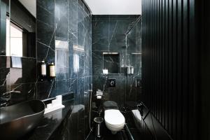 a black bathroom with a toilet and a sink at Occidental Casablanca Medina in Casablanca
