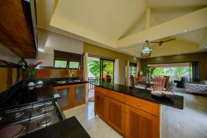 a large kitchen with wooden cabinets and a living room at Villas des Alizes Beachfront Suites in Grand'Anse Praslin