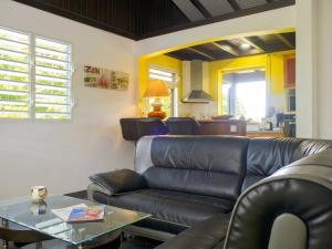 a living room with a leather couch and a table at Appartement charmant à Lamentin avec piscine partagée in Lamentin