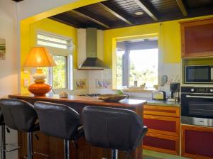 a kitchen with yellow walls and a counter with chairs at Appartement charmant à Lamentin avec piscine partagée in Lamentin
