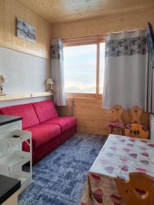 a living room with a red couch and a window at Studio chaleureux à Aime la Plagne 25 m² en montagne in Aime-La Plagne