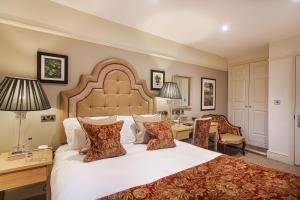 a bedroom with a large white bed with a desk and chairs at The Royal Oak Hotel, Welshpool - The Coaching Inn Group in Welshpool