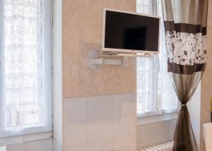 a tv on a wall in a bathroom with curtains at Studio confort à Néris-les-Bains - 18 m² avec jardin in Néris-les-Bains