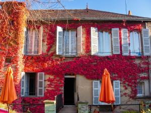 a building covered in red ivy with umbrellas in front at Studio confort à Néris-les-Bains - 18 m² avec jardin in Néris-les-Bains