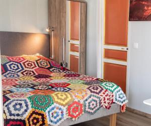 a bedroom with a bed with a colorful quilt on it at Studio confortable à Sainte-Suzanne, 20 m², balcon in Sainte-Suzanne