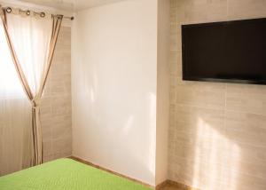 a room with a television and a green rug at Villa charmante à Le Tampon + Piscine in Le Tampon