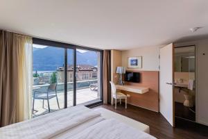 a hotel room with a bed and a desk and a balcony at Hotel Muralto Locarno in Locarno